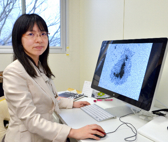 ポスドクをしていた2014年、研究室で撮影。モニターに写っているのは太陽観測衛星「ひので」が撮影した黒点の写真。黒点の内部にある輝点について研究していました。