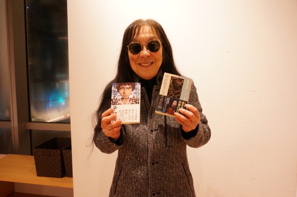 バイブルの『女たちのテロル』『何が私をこうさせたか』を持ち笑顔の浜野さん 